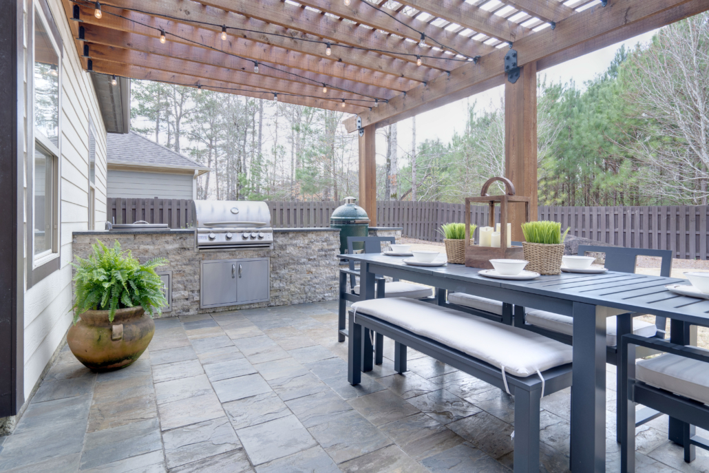 Pretty summer outdoor kitchen with table set and grilling statio